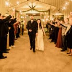 A bride and groom walking down the aisle with sparklers.