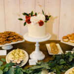 A dessert table with cupcakes, donuts, and greenery.