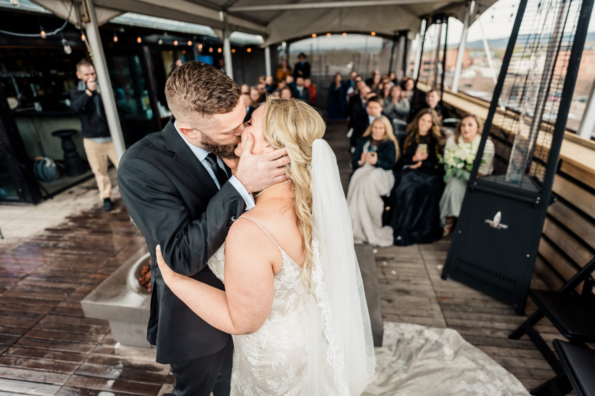 A bride and groom kissing on the roof of a building.