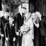 A black and white photo of the bride and groom with their family.