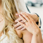 A bride is putting her wedding ring on the bride's hand.