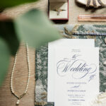 A wedding invitation and jewelry on a table.