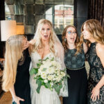 A bride and her bridesmaids laughing in the living room.
