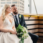A bride and groom sitting on a balcony overlooking the city.