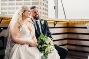 A bride and groom sitting on a balcony overlooking the city.