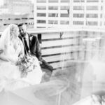 A bride and groom sitting on a balcony overlooking the city.