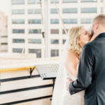 A bride and groom kissing on the roof of a building.