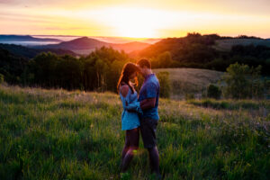A couple embracing in a grassy field at sunset.