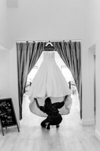 A woman putting on a wedding dress in a room.