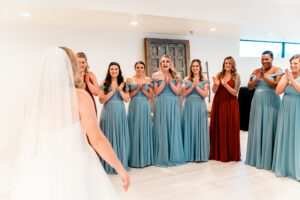 A bride and her bridesmaids clapping in front of a mirror.