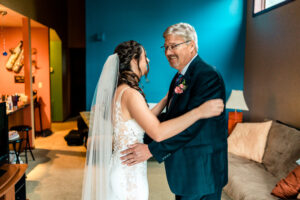 A bride and her father dance in the living room.