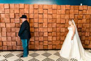 A bride and groom standing in front of a wooden wall.