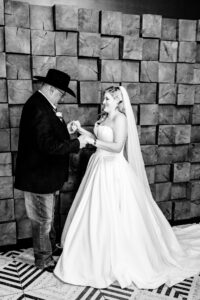 A black and white photo of a bride and groom in front of a wooden wall.