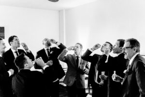 A black and white photo of a group of groomsmen drinking.