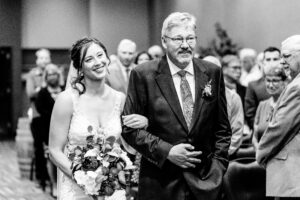 A bride walks down the aisle with her father.