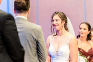 A bride and groom smile at each other during their wedding ceremony.
