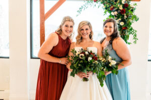 Three bridesmaids posing for a photo in front of an arch.