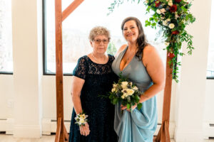 A bride and her mother standing in front of a wedding arch.