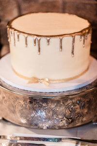 A wedding cake with gold drips on it.