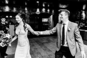 A bride and groom holding hands in a black and white photo.