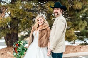 A bride and groom wearing cowboy hats and fur coats.