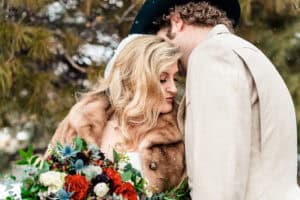 A bride and groom kissing in the snow.