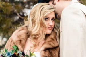 A bride and groom kissing in the snow.
