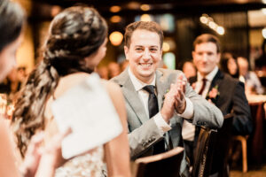 A groom clapping at a wedding reception.