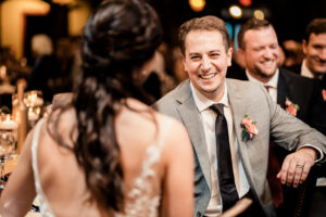 A bride and groom smiling at each other at a wedding reception.