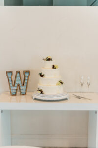 A wedding cake is sitting on a table next to the letter w.