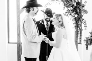 A bride and groom exchange vows in front of a cowboy hat.