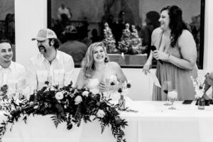 A black and white photo of a group of people laughing at a table.