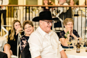 A man wearing a cowboy hat at a wedding reception.