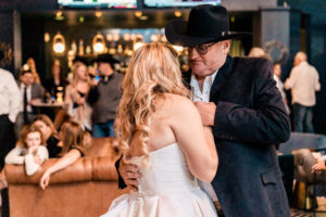 A man in a cowboy hat dancing with his bride.