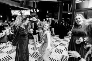 A black and white photo of a group of women dancing at a wedding.