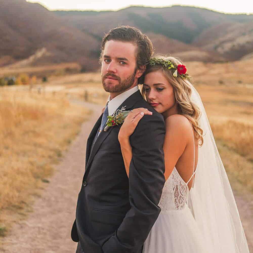 A Littleton Wedding Photographer captures a bride and groom posing on a dirt road in the mountains.