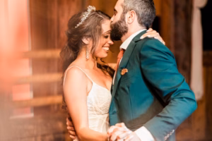 A bride and groom in formal attire share a close, joyful embrace and dance indoors, with the groom kissing the bride's forehead—an unforgettable moment beautifully captured by a Vail Wedding Photographer.