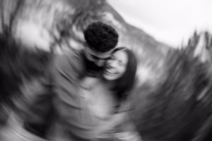A blurred black and white photo of two people embracing outdoors, with a swirling motion effect creating a sense of movement.