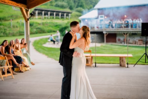 A bride and groom share a first dance under a pavilion while guests watch and take photos at this enchanting Horstmann Homestead wedding.